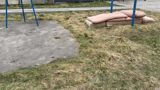 Courtyard pullup bar with sofa mats, spring day blue metal turnstile, stacked pink cushions from old sofa tossed on grass