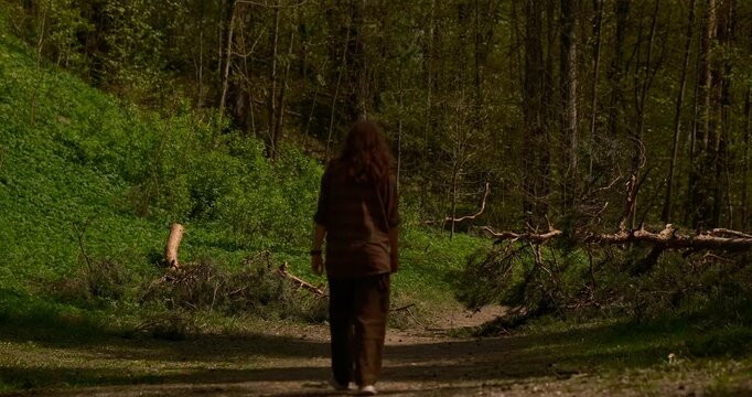 cinematic summer forest scene featuring a teenage girl with natural red hair walking away along a narrow trail surrounded by tall pine trees. Wearing a casual plaid shirt