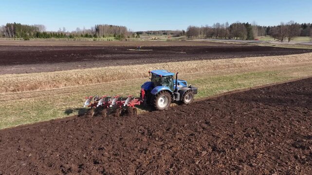 The tractor is performing soil cultivation. Aerial photo.
