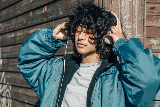 Latino Hispanic teenager with headphones on the wall in the street