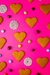 Fototapeta premium Top view of candies and heart shaped cookies on a vibrant pink background. Dessert photography, sweet treats.