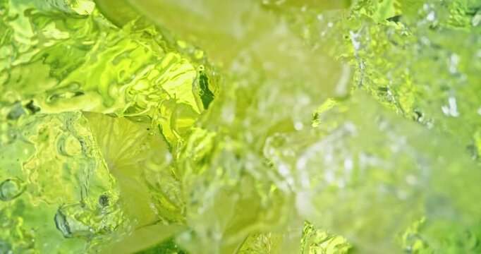 Super slow motion 1000fps video of lime slices and crushed ice falling into rippling water, creating a fresh sparkling splash, perfect for drink, cocktail, beverage and summer visuals.