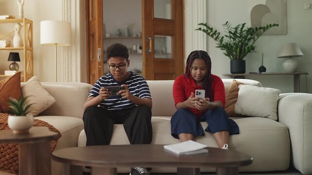 African American siblings playing video games on their phones, digital lifestyle
