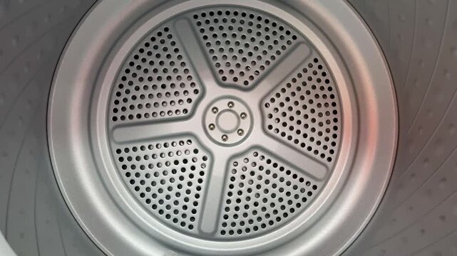 Close-up steel drum interior rubber seal visible, showroom display of new dryer drum with perforated stainless surface and circular