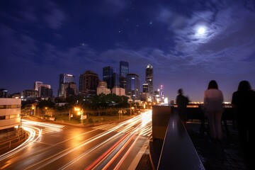 Fototapeta premium Nighttime cityscape with people overlooking road and skyscrapers