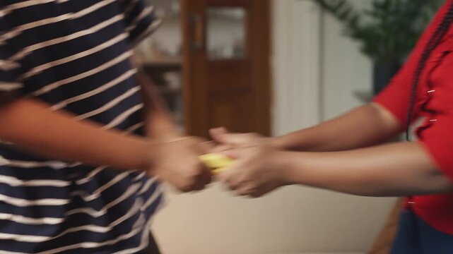 African American children struggling over a gamepad at home, sibling rivalry