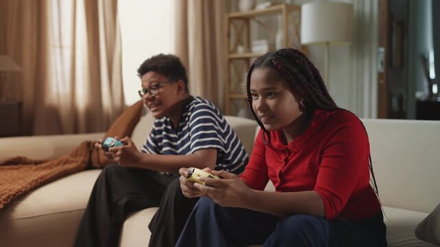 African American siblings celebrating video game victory, high-fiving each other