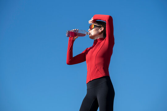 Sporty woman drinking water after exercise outdoors