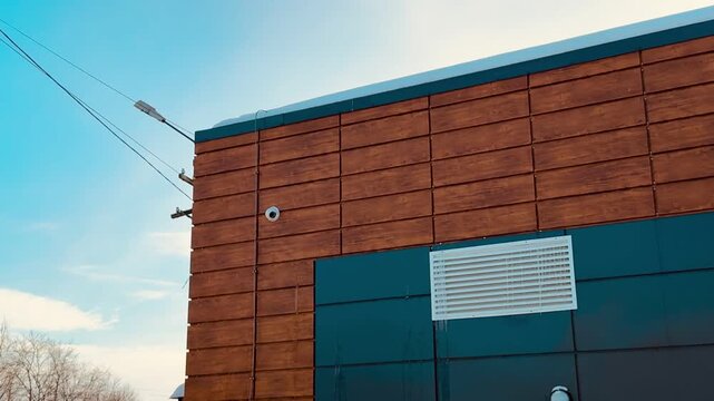 Snow covered storage unit with iron door. Security camera mounted above entrance monitors quiet winter yard, brick and metal