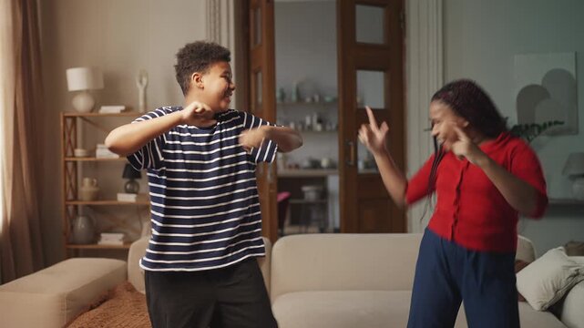 African American girl and her brother happily dancing together at home party