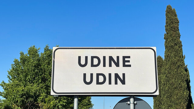 Bilingual signage, the sign shows the name of the city in Italian, Udine, and in the Friulian language, Udin.