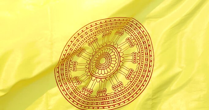 Buddhist flag with Dharmachakra symbol waving in the wind representing faith, Buddhist yellow flag, spirituality, peace, meditation and religious cultural concept, close-up