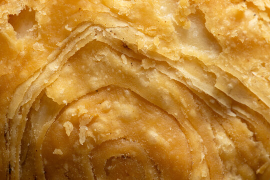 Macro texture of crispy layered puff pastry dough background,Extreme close-up texture of golden brown curry puff pastry, showing detailed crispy layers and crunchy surface background.
