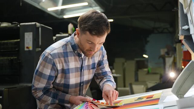 Male graphic designer matching colors at print plant