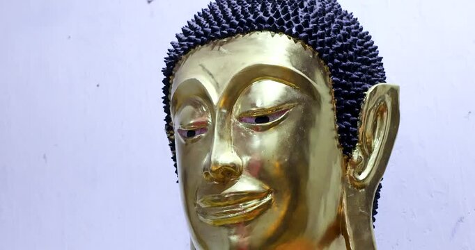 Golden Buddha statue details showing robe texture and peaceful facial expression, symbolizing spirituality, faith, Buddhism culture and Thai heritage, close-up