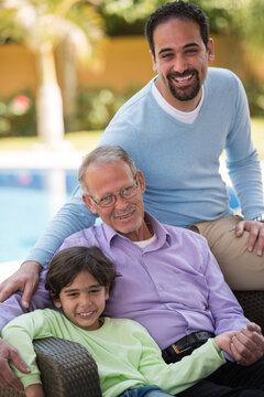 Happy multigenerational family portrait with grandfather, father and grandson relaxing by the pool