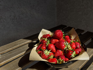 Bowl of fresh strawberries on wooden table in sunlight. Concept of summer harvest, healthy eating, rustic food styling and seasonal freshness © Phlegmatic Tigress