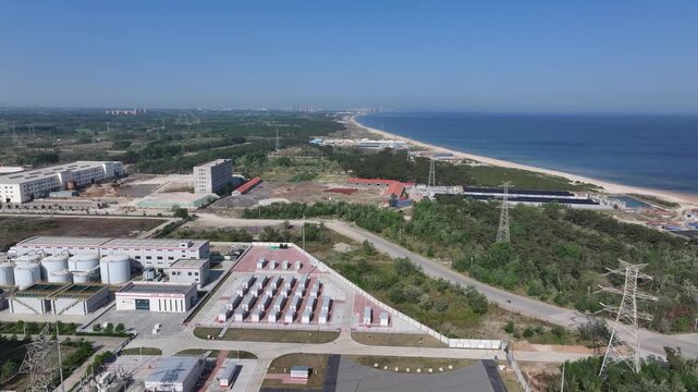 Aerial view of coastal industrial zone with storage tanks and power infrastructure