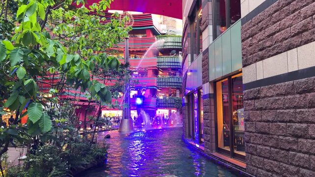 Beautiful fountain show illuminates Canal City Hakata in Fukuoka Japan. Dynamic purple lights glow over the artificial river inside the commercial complex. 