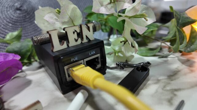 A yellow ethernet cable is plugged into a black network device labeled 'LEN'.