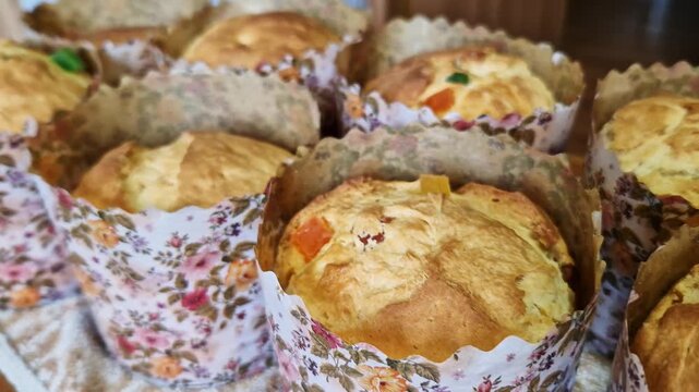 A close-up view of freshly baked sweet breads with candied fruit in decorative floral paper molds. Concept of Easter celebration, homemade bakery, traditional holiday food, and festive atmosphere