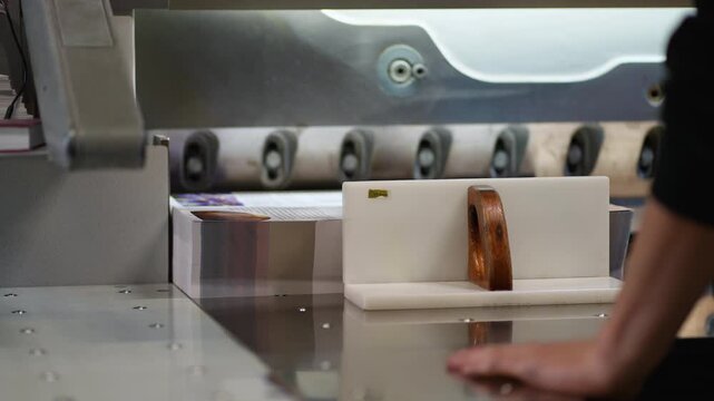 Printing house worker cutting paper stack