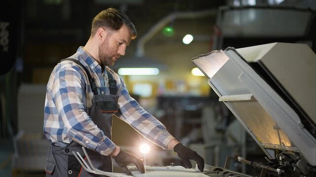 Printing house worker operating industrial offset machine