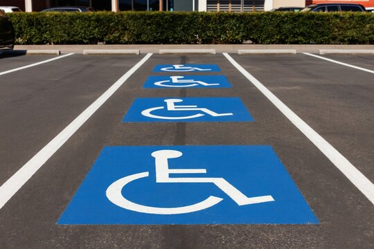 Several handicap parking spaces marked with blue squares and white wheelchair symbols. These designated areas offer convenient, close access for disabled drivers in paved lot with white line markings.