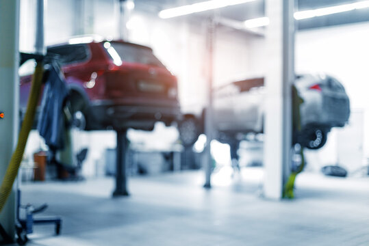 Two vehicles elevated for maintenance in auto repair shop, blur background