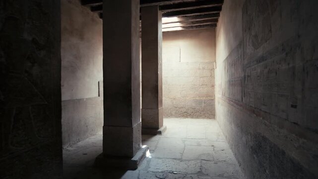Corridor of Mereruka mastaba tomb at Saqqara, Egypt, with large painted red relief figure of tomb owner, smaller scene registers and dark doorway leading deeper inside.
