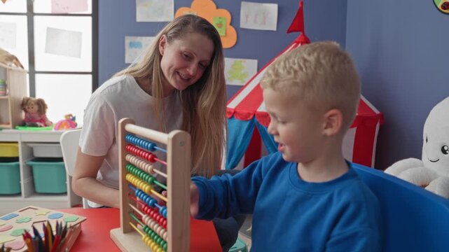 Woman teacher leaning and smiling while boy plays with abacus in building; gentle patient learning joy.