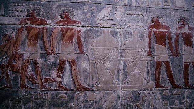 Close-up of detailed limestone relief carving inside tomb of Kagemni at Saqqara, Egypt, depicting ancient Egyptian male figures with tools, faint traces of original red pigment.