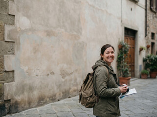 Obraz premium Happy Woman Traveler with Camera and Map Exploring Old Town Street