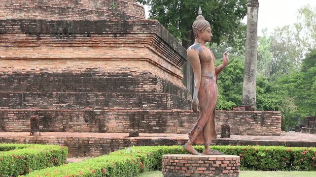 Walking Buddha statue at Wat Sa Si in Sukhothai Historical Park Thailand.