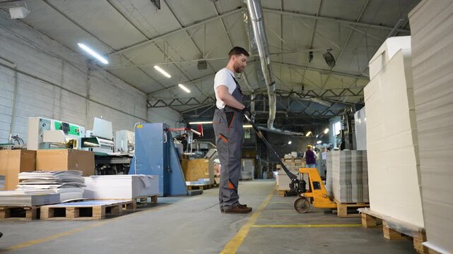 Print plant worker moving paper stack with pallet jack