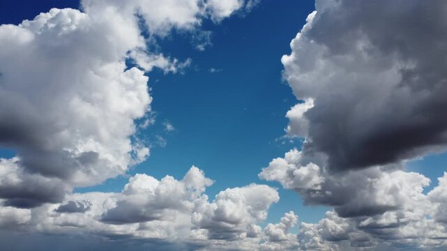 4K aerial drone view of white and grey cumulus clouds framing a deep blue sky, cinematic transition through dramatic cloudscape, high altitude atmospheric weather background, peaceful sunny day with c