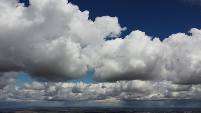 4K aerial drone view of majestic white cumulus clouds over a vast blue sky, cinematic transition through the atmosphere, beautiful summer day weather background, high altitude bird's eye view, peacefu
