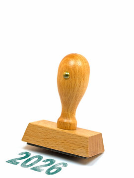 Holzstempel mit dem Aufdruck 2026 vor wei&szlig;em Hintergrund