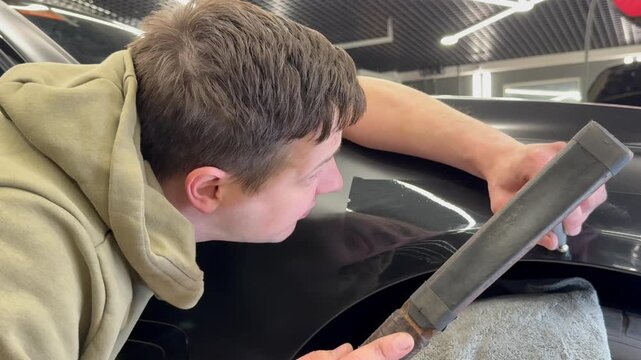 PDR. Process of paintless dent repair on car body. The mechanic at the auto shop with tools to repair dents in car body. Body repair. A specialist repairs a dent on the car body without painting. PDR.