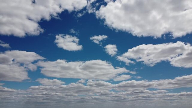4K aerial drone view of white fluffy clouds against a vibrant blue sky, cinematic high altitude flight, beautiful cloudscape background for video projects, bright sunny day atmosphere, UHD nature foot