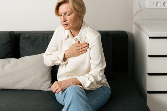 Mature woman experiencing chest pain and heavy breathing