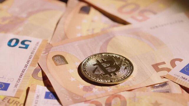 Bitcoin coin spinning on a group of euro banknotes