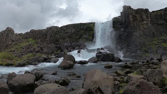 Cinematic 4K shot of Oxararfoss waterfall with rocky riverbed