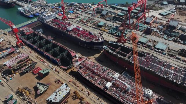 Large shipyard with multiple vessels under construction including steel structures and cranes
