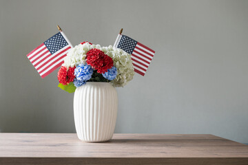 Fototapeta na wymiar Patriotic flower bouquet with American flags in white vase on table