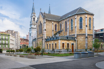 Fototapeta premium Exterior rear and side view of the Neo-Gothic New Church of Sabugo (Church of Saint Thomas of Canterbury) in Aviles, Asturias, Spain. The photograph shows the stone apse, pointed arch windows, tall sp