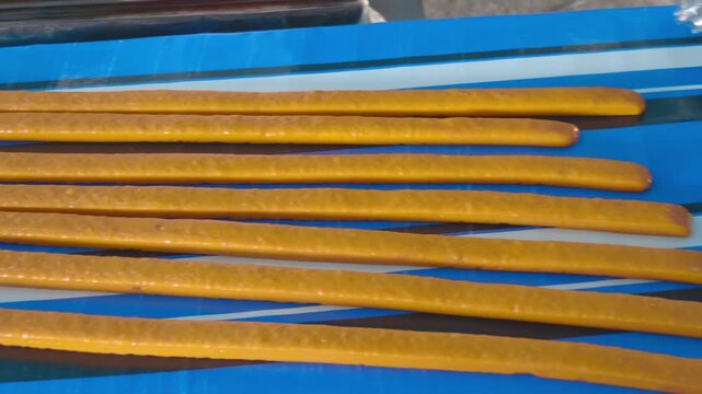 Long orange color strips of freshly made coconut candies lay on the table cooling down and getting ready to be tasted and then packed for sale