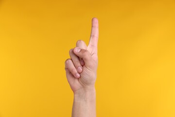 Naklejka premium Man pointing upwards on yellow background, closeup