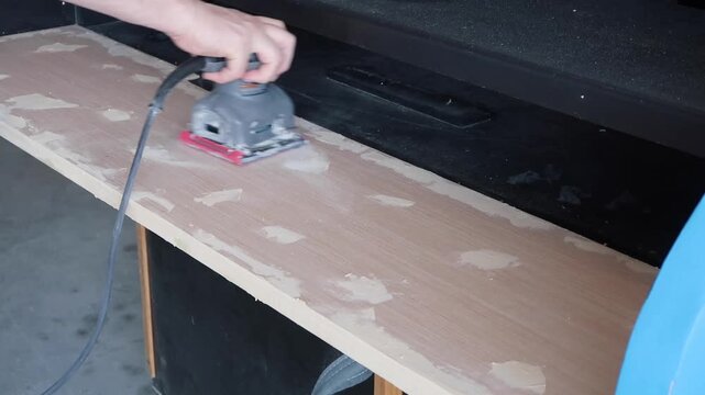 sanding wood filler on a piece of plywood