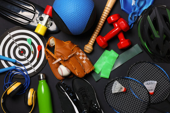 Different sports equipment, water bottle, penny board, sneakers and headphones on black background, flat lay